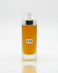 A clear glass bottle with a pump dispenser containing yellow liquid, labeled F79, placed on a wooden surface with floral background.