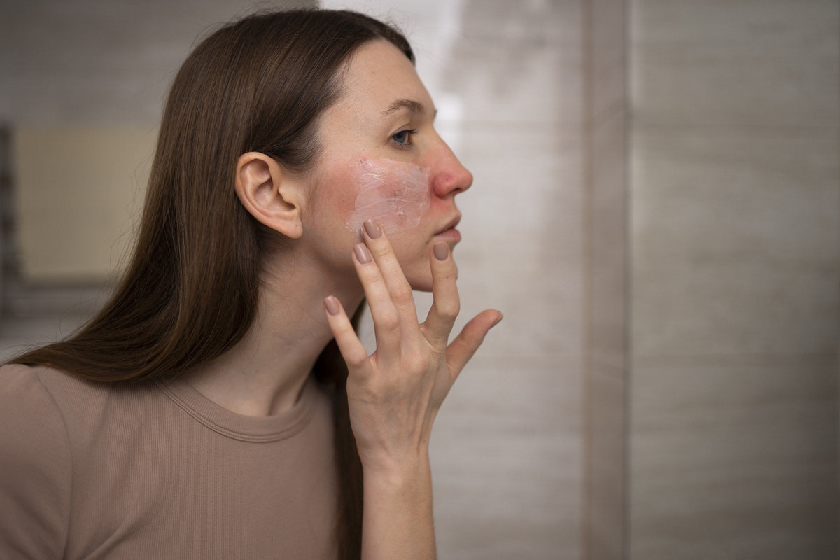 Woman applying moisturizer to calm red, reactive skin across the cheek