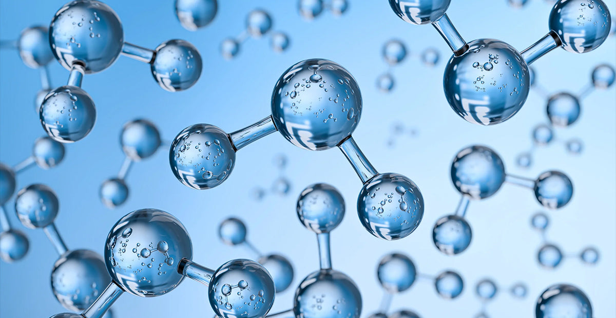 Hyaluronic acid serum and fresh botanicals on a warm neutral surface