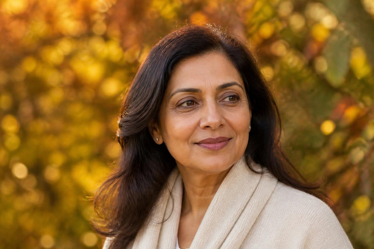 A woman in her forties outdoors in autumn light, skin clear and even in texture