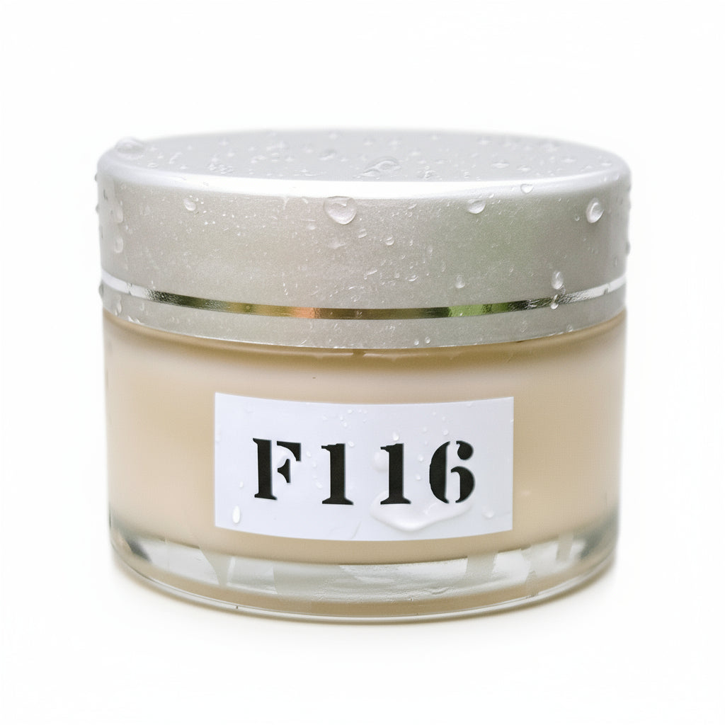 A clear jar of F116 CHOCOLATE AND BLUEBERRY FACE BALM placed on a bed of green pine needles with water droplets on it, indicating freshness.