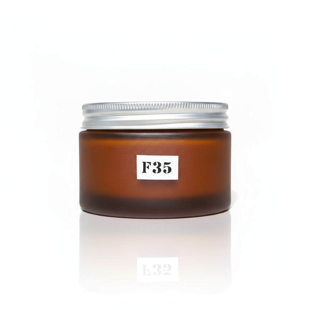 A jar of F35 Sandalwood Face and Body Scrub placed on a wooden surface with floral background.