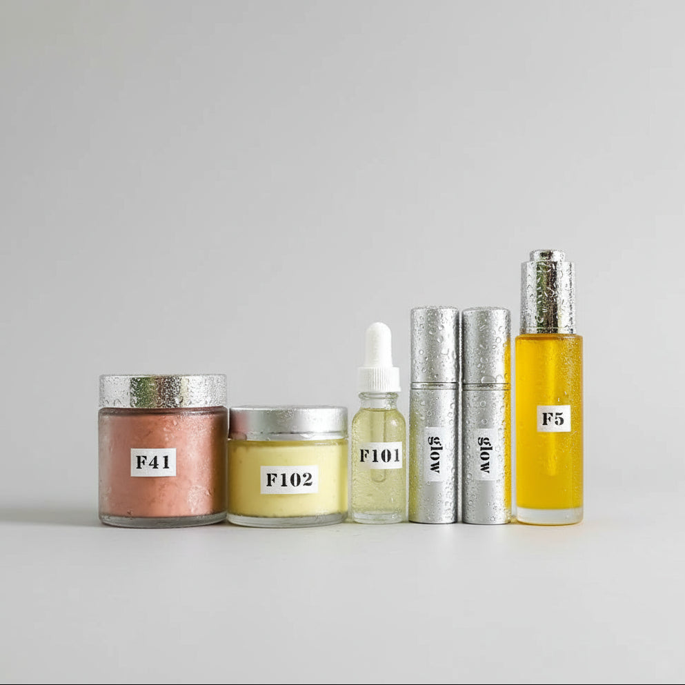 A series of skin care products arranged outdoors, including bottles labeled F51, F102, and others, with a background of green plant leaves.